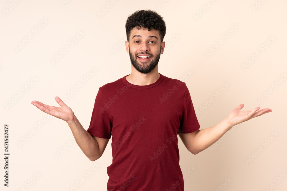 Young Moroccan man isolated on beige background with shocked facial expression Young Moroccan man isolated on beige background with shocked facial expression
