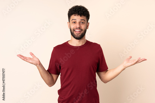 Young Moroccan man isolated on beige background with shocked facial expression