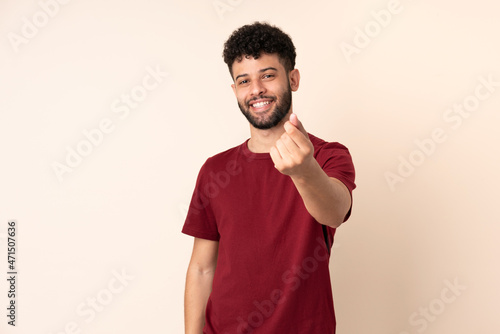 Young Moroccan man isolated on beige background making money gesture