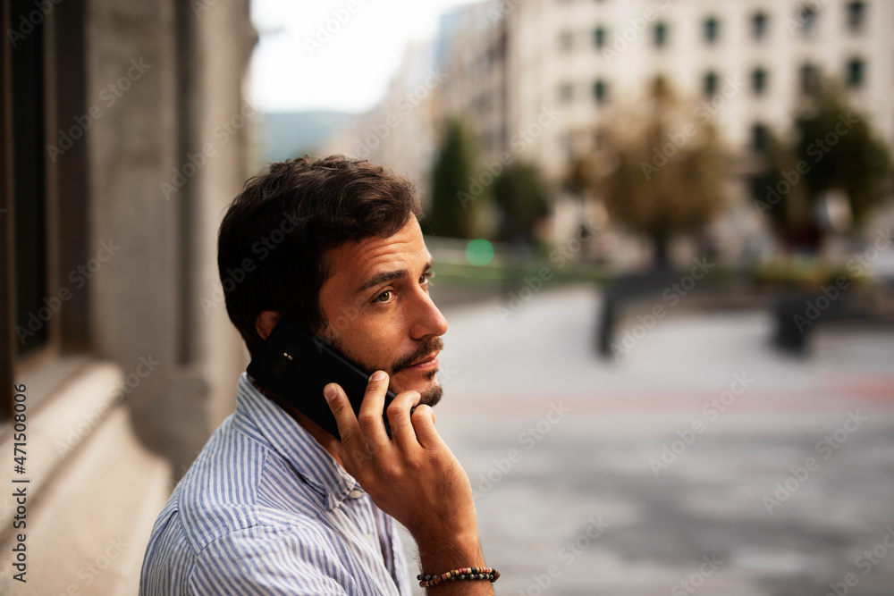 Young modern man using the phone outdoors. Fashion happy man enjoy outdoors..