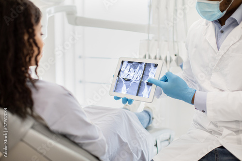 Black Dentist Doctor Showing Teeth Xray On Digital Tablet To Female Patient