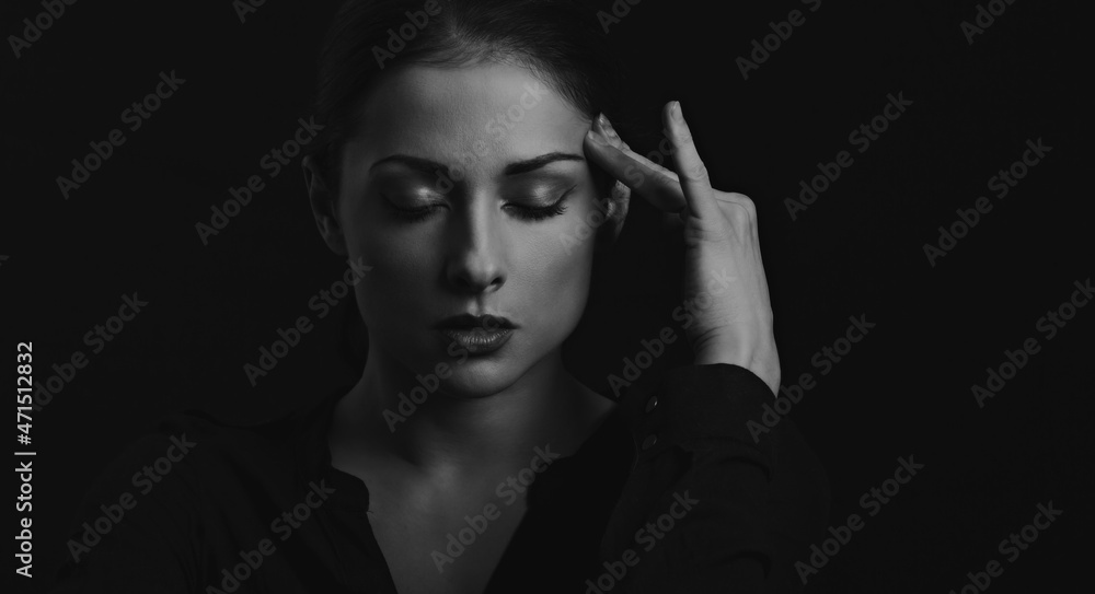 Business strong thinking woman find the answer in clever mind with closed eyes with fingers near the face  in black t-shirt on dark shadow black background. Closeup