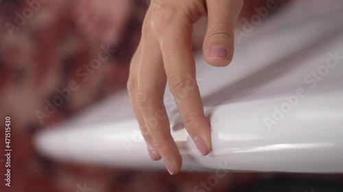 Wallpaper Mural A man with a sloppy pink manicure touches a white surfboard punched by a blow. Close-up of a girl touching a crack on a surfboard, after damage. A person prepares a surfboard for repair. Slow motion. Torontodigital.ca