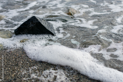 Sea foam near rocks on the beach at the Pacific Northwest Gulf Islands in British Columbia, Canada photo