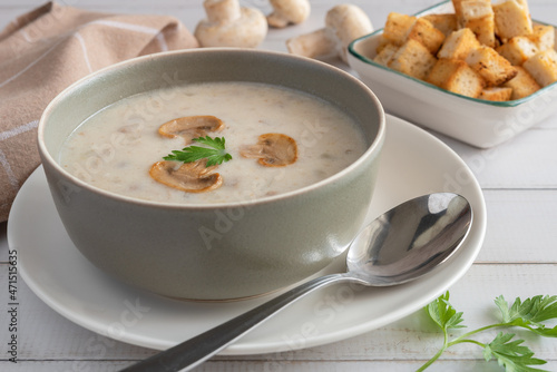 Cream of mushroom soup in a gray bowl on a wooden background.