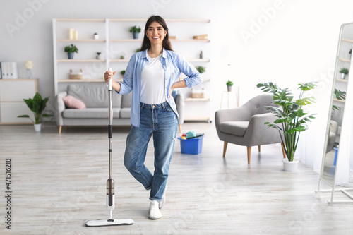 Portrait of cheerful woman cleaning floor with spray mop, posing