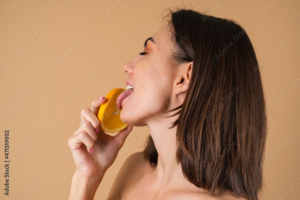 Portrait of a young woman on a beige background with natural warm make-up and smooth clean skin, holding orange circles Portrait of a young woman on a beige background with natural warm make-up and smooth clean skin, holding orange circles