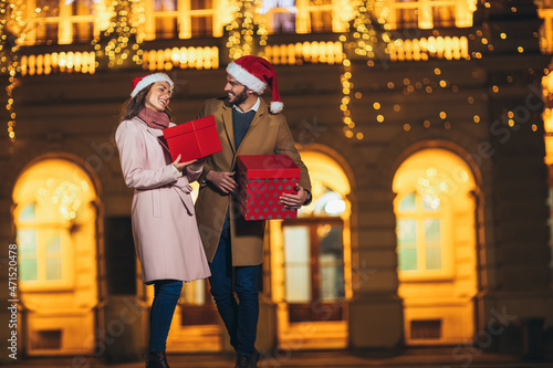 Young romantic couple holding gift box having fun outdoors in winter before Christmas.