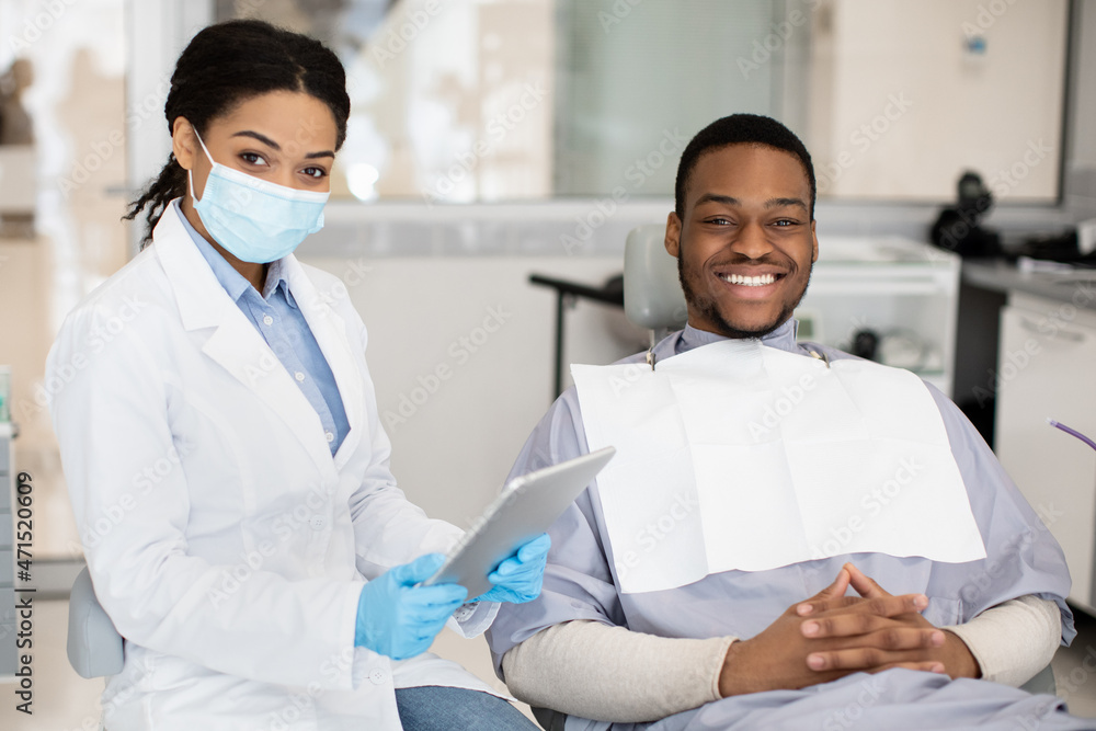 Dental Insurance Concept. Black Dentist Woman And Male Patient Posing In Clinic Dental Insurance Concept. Black Dentist Woman And Male Patient Posing In Clinic