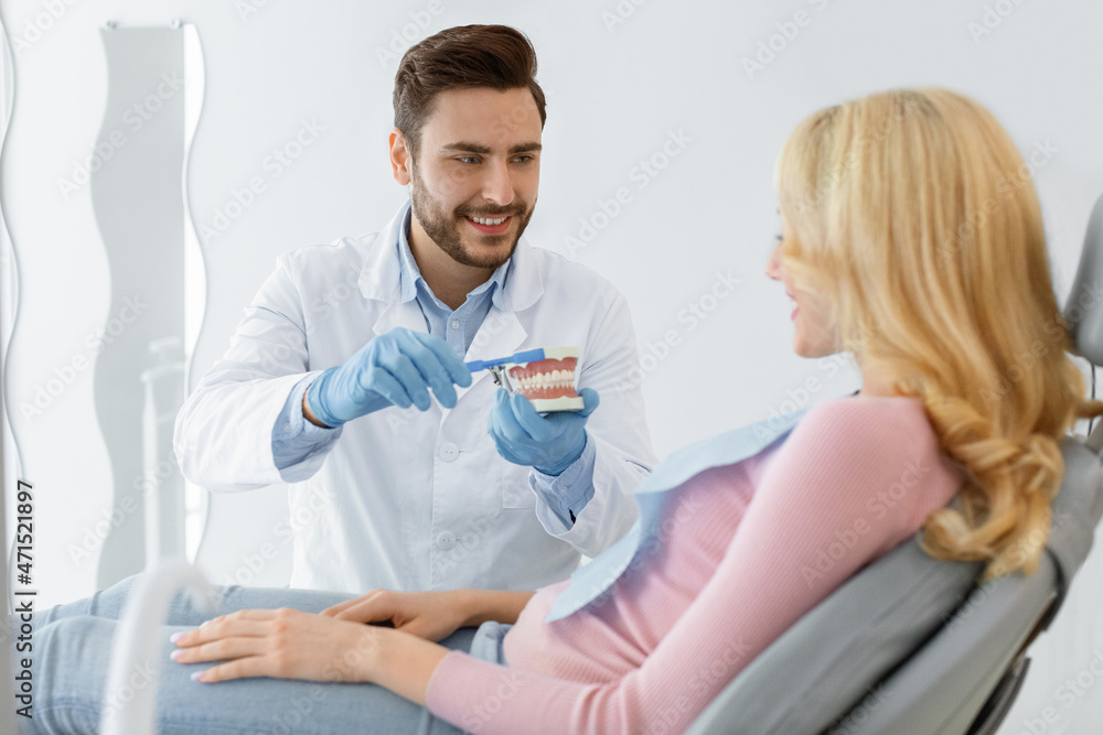 Fototapeta premium Dentist holding jaw and tooth brush, having conversation with patient