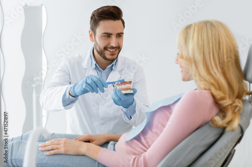 Dentist holding jaw and tooth brush  having conversation with patient