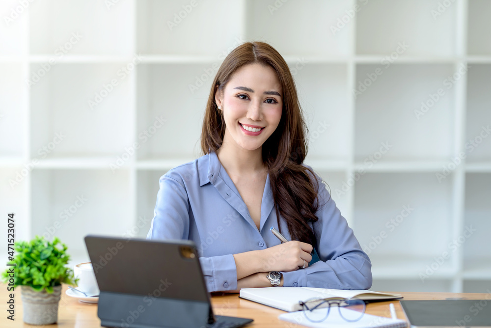 Beautiful young Asian businesswoman sitting looking at camera with laptop in office. Beautiful young Asian businesswoman sitting looking at camera with laptop in office.