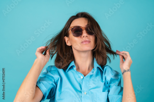 Young woman in a blue shirt on a background in sunglasses, fashionably stylish posing