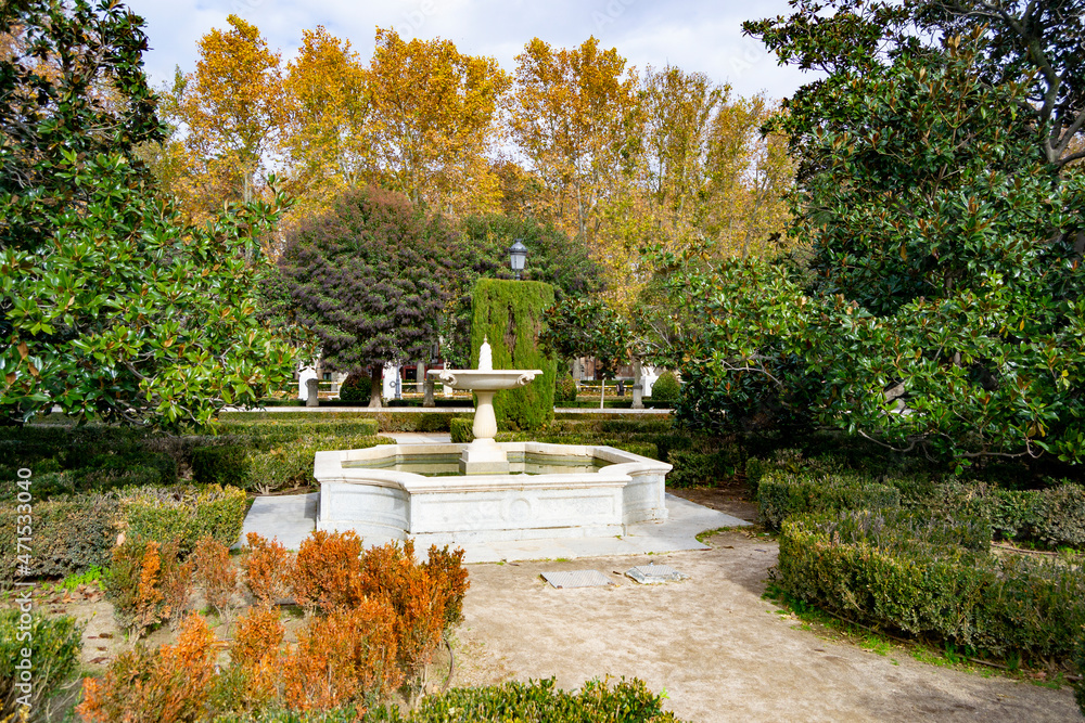 Stone fountain with trees and autumn vegetation around it. Next to the Royal Palace of Madrid, in Spain. Europe. Horizontal photography.