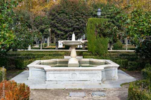 Stone fountain with trees and autumn vegetation around it. Next to the Royal Palace of Madrid, in Spain. Europe. Horizontal photography.