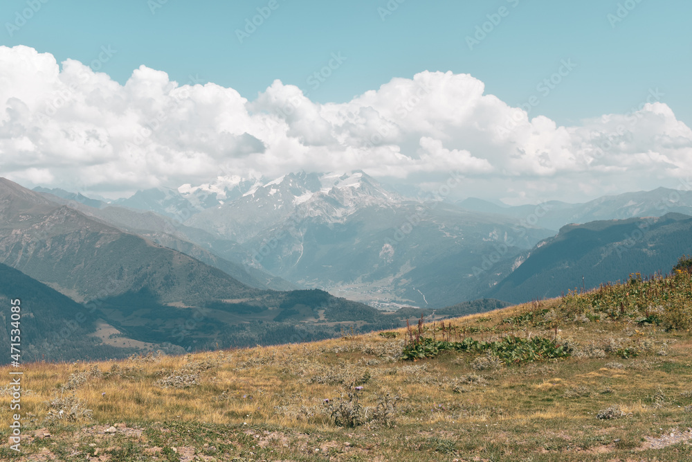 Summer mountain landscape near Mestia, Svaneti region, Georgia, Asia. Snowcapped mountains in the background. Blue sky with clouds above. Georgian travel destination