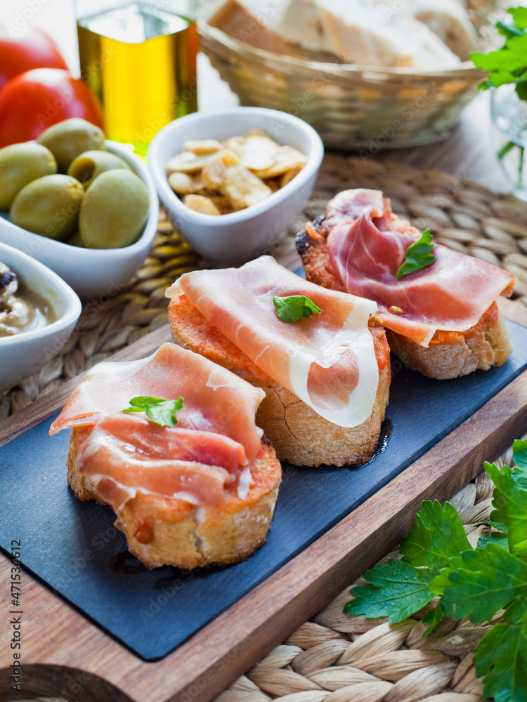 Spanish cuisine tapas with Serrano Ham and tomatoes - montadito de tomate y jamon serrano.