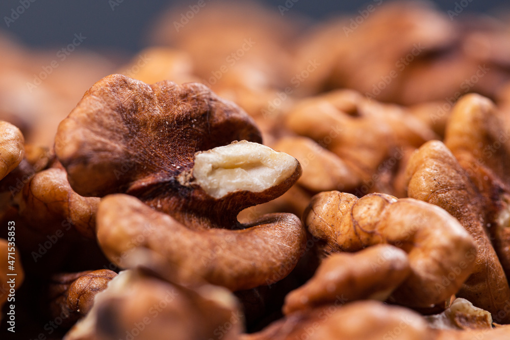 Pieces of peeled textured walnuts against dark background. Closeup shot. Pieces of peeled textured walnuts against dark background. Closeup shot.