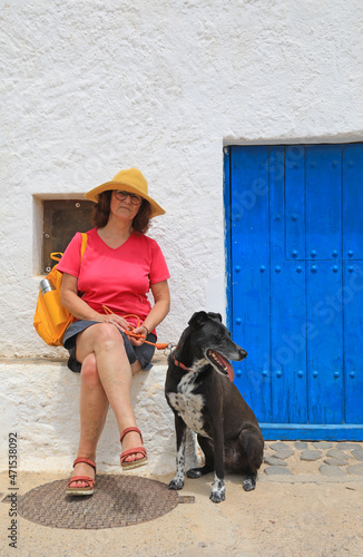 mujer turista con perro negro sentada delante de una casa blanca con puerta azul almería cabo de gata nijar 4M0A5688-as21
