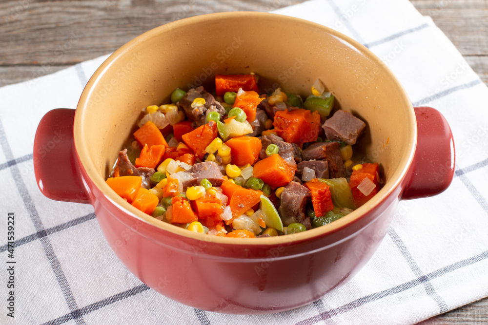 Stewed beef tongue with vegetables in a saucepan on the table. horizontal Stewed beef tongue with vegetables in a saucepan on the table. horizontal