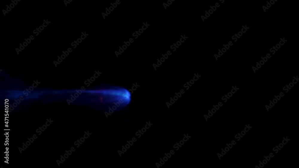 Flammable liquid catches fire and burns on black studio background. Gas fire and combustion close up. Spot of gasoline ignites with flash and burns with blue yellow light in dark in slow motion.