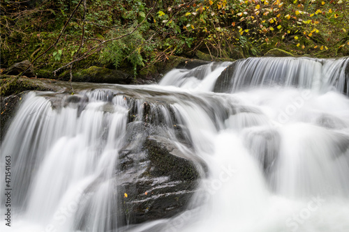 Fototapeta Naklejka Na Ścianę i Meble -  Long exposure of a waterfall flowing through the woods at Watersmeet in Exmoor National Park