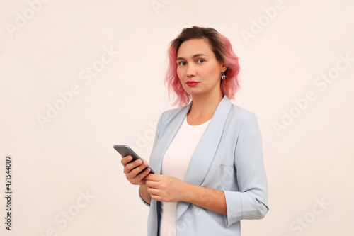 a young woman with pink hair using a mobile phone on a gray background