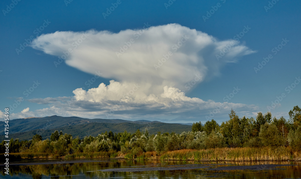 A strange cloud is reflected in the water of a lake. The lake is located in Gorj, Romania.