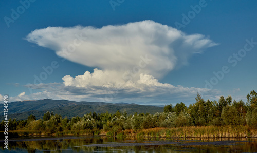 A strange cloud is reflected in the water of a lake. The lake is located in Gorj, Romania. photo