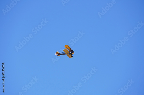 vintage biplane flying high in a bright blue sky