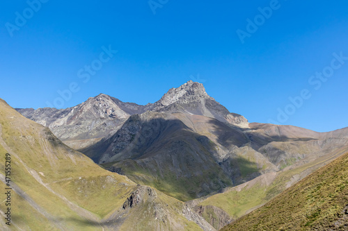 A panoramic view on the sharp ridges of the high mountain peaks of the Chaukhi massif in the Greater Caucasus Mountain Range in Georgia, Kazbegi Region. Wanderlust. Clear Sky. Hiking