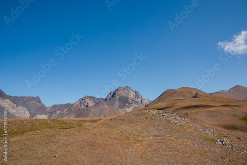 A panoramic view on the mountain peaks of the Chaukhi massif in the Greater Caucasus Mountain Range in Georgia, Kazbegi Region. A barren meadow leading over the Chaukhi Pass. Wanderlust. Hike