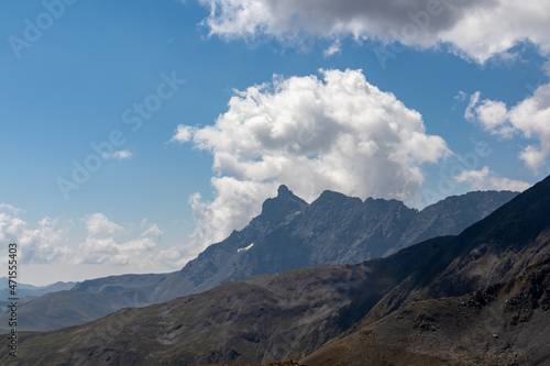 A panoramic view on the sharp ridges of the mountain peaks of the Chaukhi massif in the Greater Caucasus Mountain Range in Georgia, Kazbegi Region. Clouds emerging over the Chaukhi Pass. Ar?te. Hike