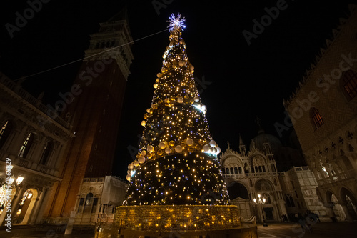 Christmas tree with lights and gold colored balls. Colorful background of San Marco square in Venice. Theme concerning the symbols of Christmas