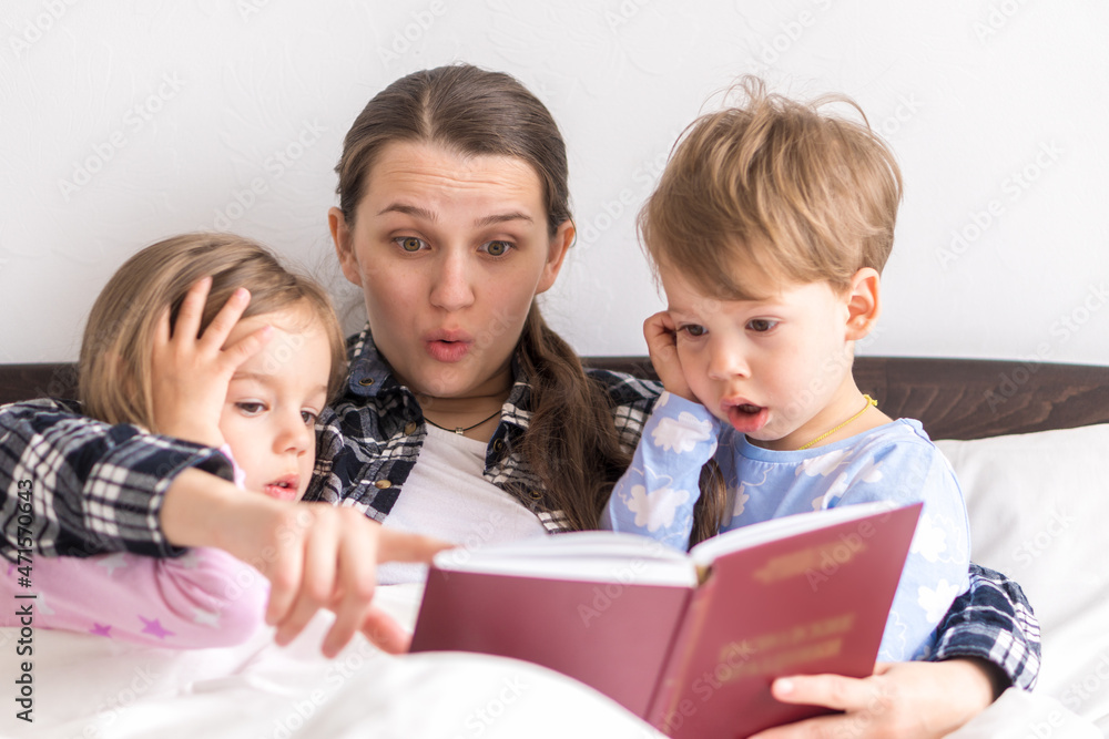 happy family. Close up loving mother lying with daughter son two kids pajamas in bed children reading interesting storybook, preschool smiling kid girl enjoy fairytale before go to sleep good pastime happy family. Close up loving mother lying with daughter son two kids pajamas in bed children reading interesting storybook, preschool smiling kid girl enjoy fairytale before go to sleep good pastime