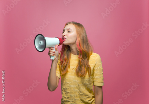Young girl shouting in megaphone to announce news, information on pink studio background. Advertising, promotion concept