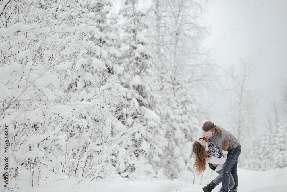 Hipster couple in love hugs each other in a winter park. Winter holidays. Christmas holidays outdoors in the forest. Copy space