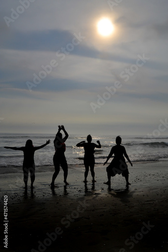 Silhouette of 4 women jumping on a beach at sunset