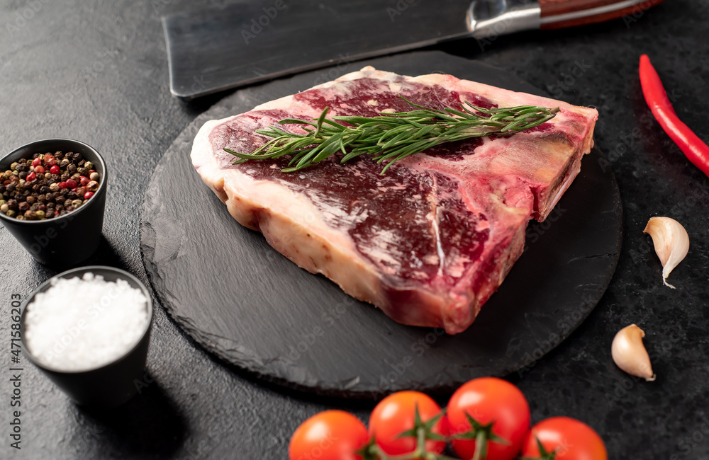 Raw t-bone steak with spices on a stone background. dry-aged steak