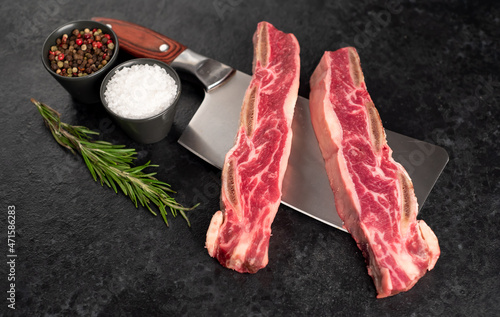 raw marbled beef ribs on a knife on a stone background