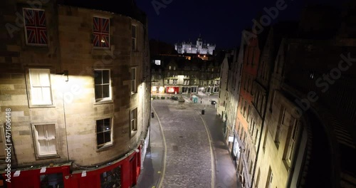 Famous Victoria street at night a popular venue with traditional shops and an icon of Edinburgh, Scotland, UK. Night streets of Scottish capital, Edinburgh castle in the background