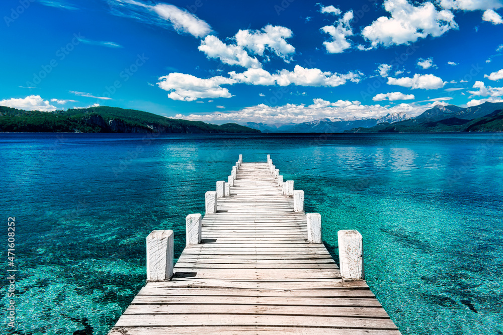 Obraz premium white dock on crystal clear lake with mountain in background