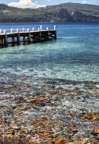 pier on the lake with colorful beach and mountain in the background
