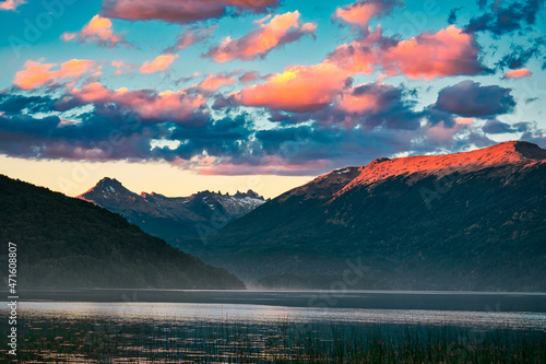 sunset in lake with mountains in the background and sky with orange clouds