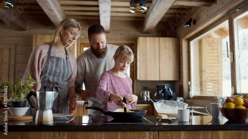 Small girl with parents cooking together indoors, winter holiday in private apartment. photo