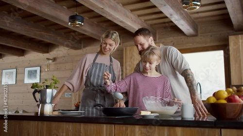 Small girl with parents cooking together indoors, winter holiday in private apartment. photo