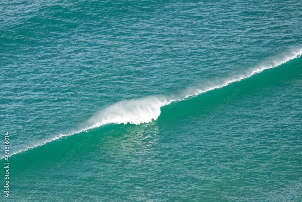 Single wave diagonally across frame and breaking in the middle from elevated position Single wave diagonally across frame and breaking in the middle from elevated position