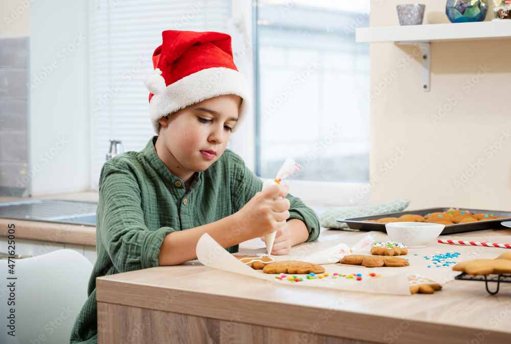 Child boy decorate honey gingerbread cookies on table at kitchen. Icing of Christmas bakery. Concept expectation for Christmas holiday. Child boy decorate honey gingerbread cookies on table at kitchen. Icing of Christmas bakery. Concept expectation for Christmas holiday.