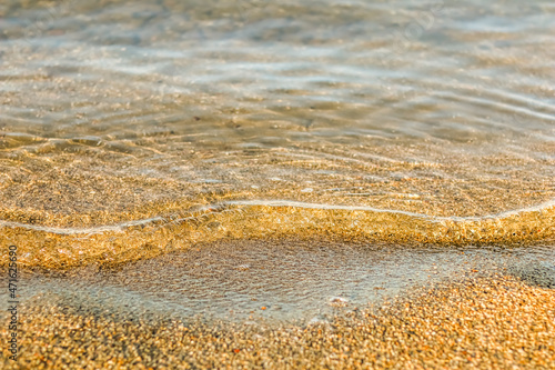 Flowing wave on the sea sandy beach at sunset. Summer vacation background and coastal nature concept