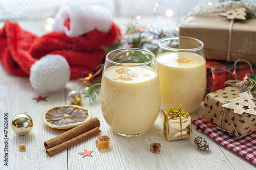 Two glasses of eggnog on a white wooden table next to the Christmas presents. Sweet egg dessert. Christmas breakfast. Selective focus